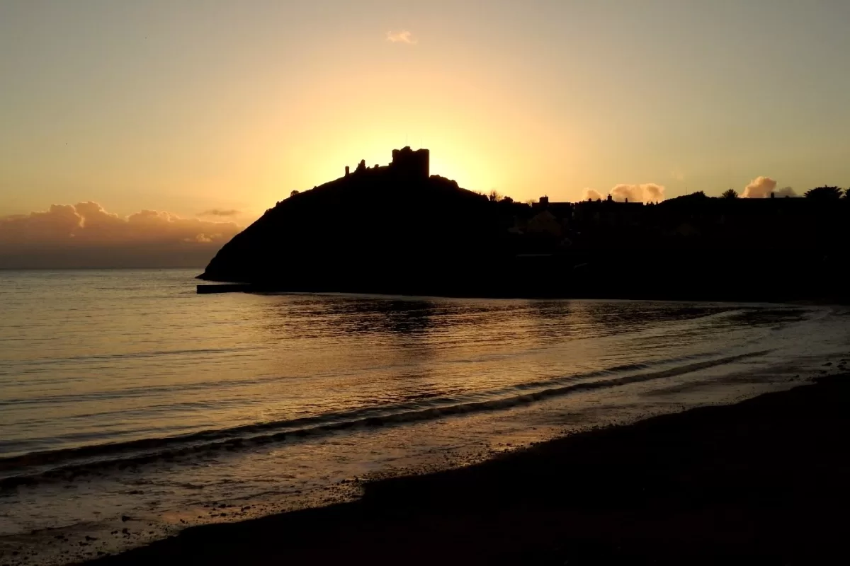 Criccieth Castle in silhouette at sunset, seen from the beach
